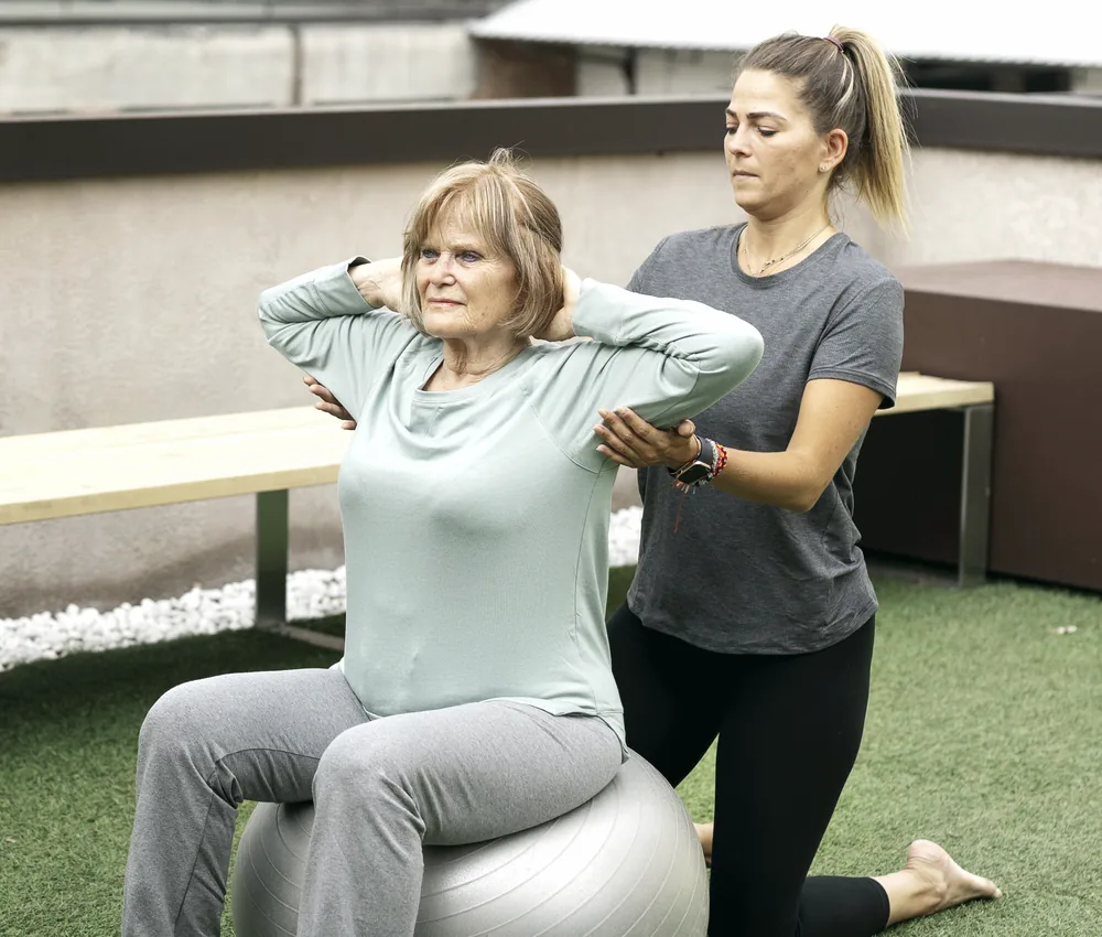 Paciente idosa em exercício terapêutico acompanhada pela fisioterapeuta